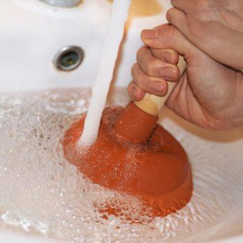 Woman using plunger on a clogged sink drain